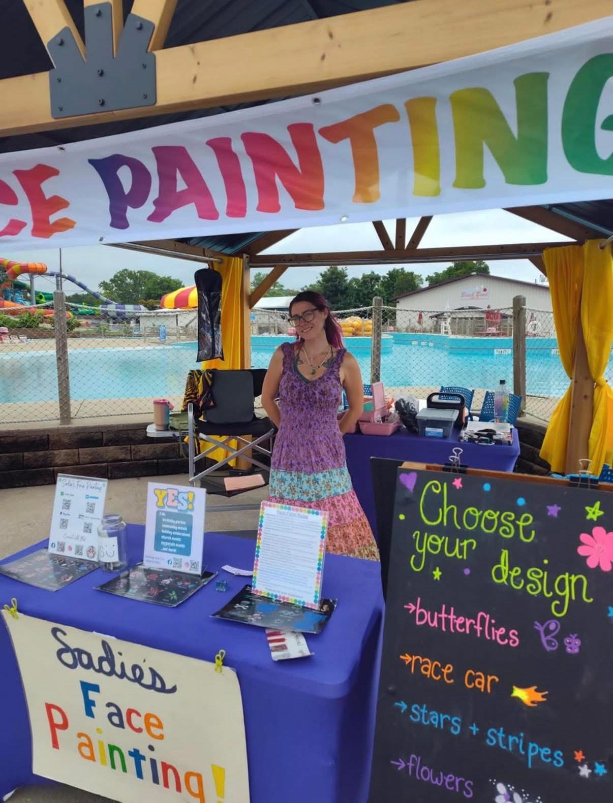 Sadie at her booth by the pool with a Choose your design chalkboard menu