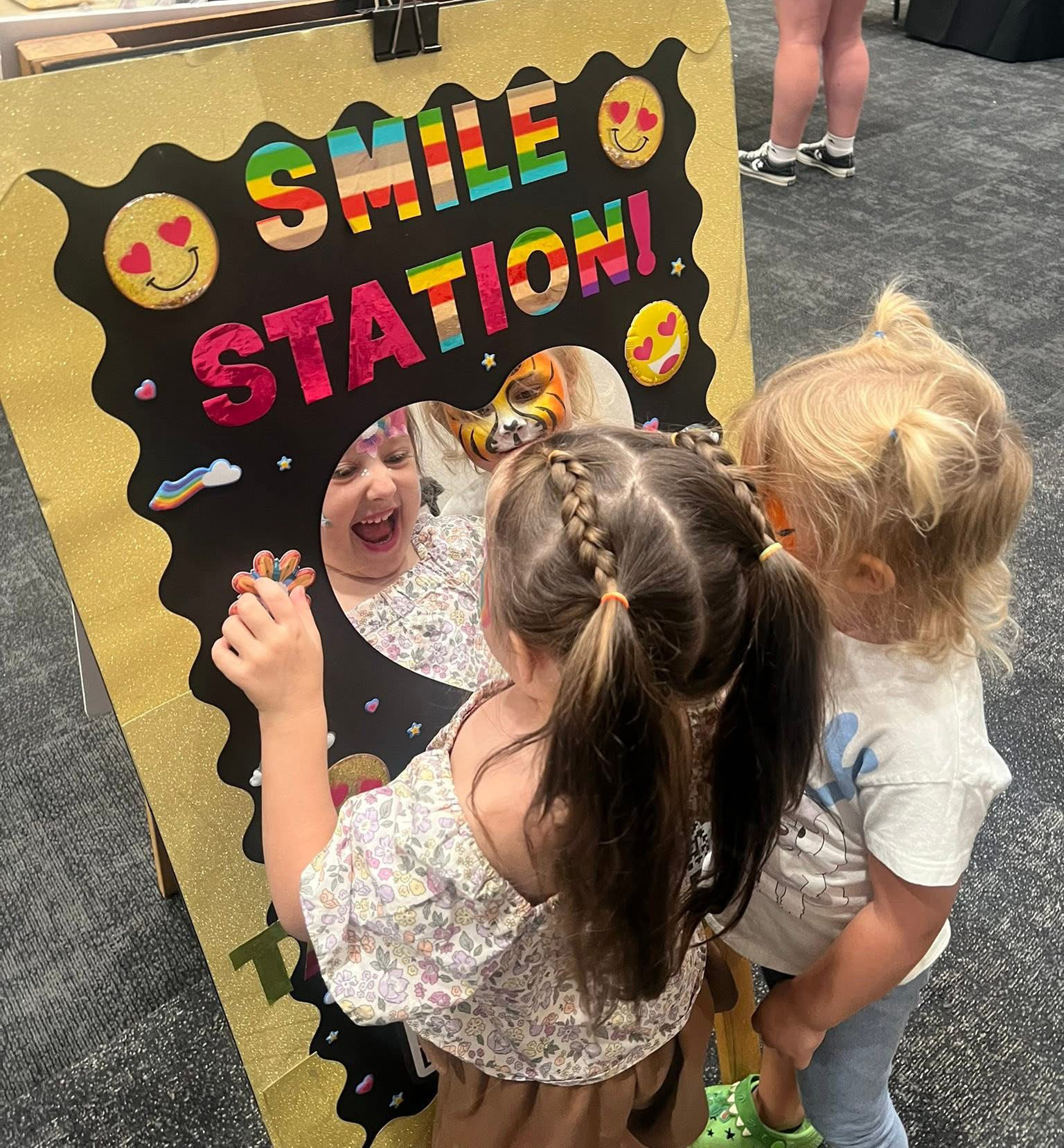 Kids gathered around the Smile Station, excited to see their face paint